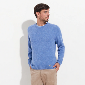 Man wearing a blue sweater and beige pants on a white background