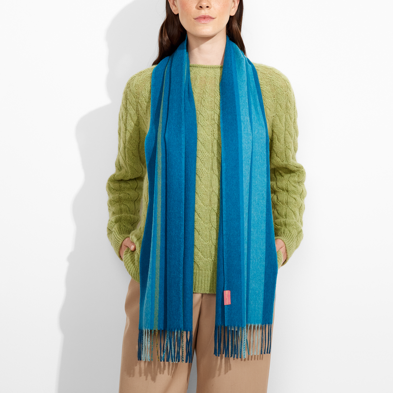 Woman wearing a green sweater and blue scarf on a white background