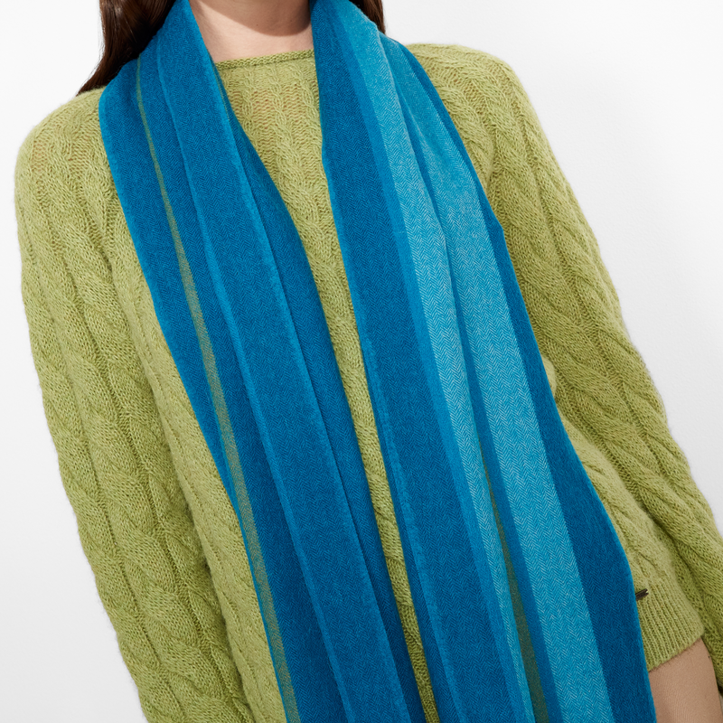 Woman wearing a green sweater and blue striped scarf on a white background