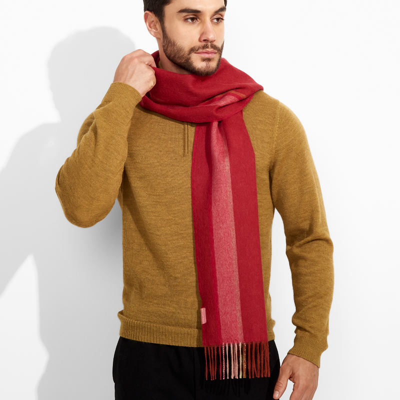 Man wearing a mustard sweater and red scarf against a white background