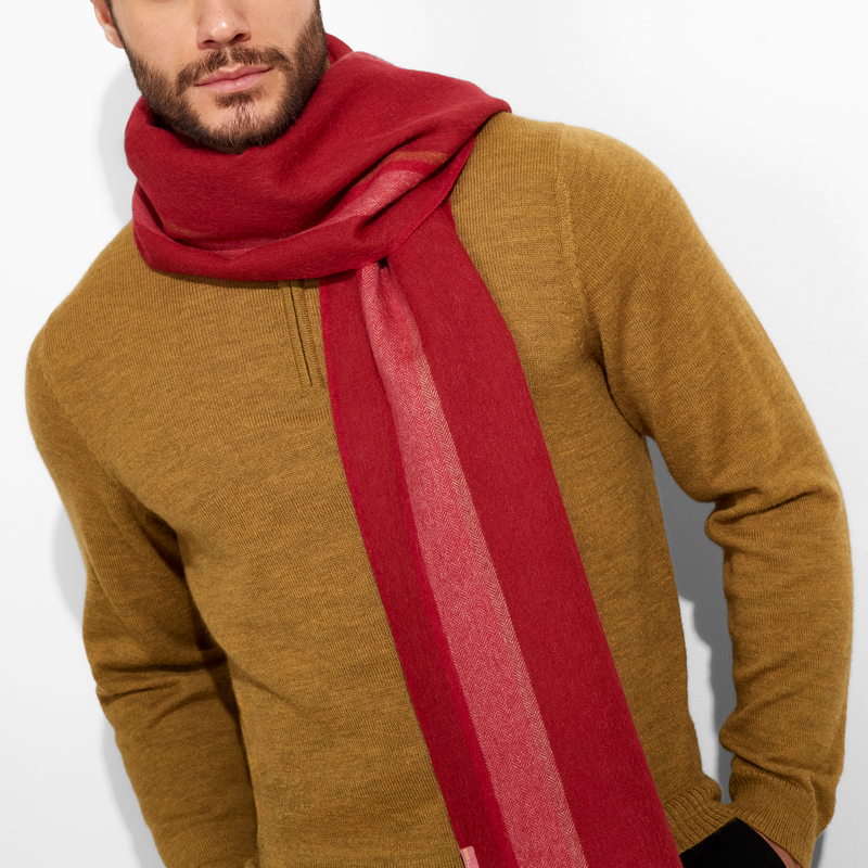 Man wearing a mustard sweater and red scarf against a white background