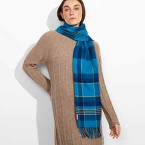 Woman wearing a blue plaid scarf over a beige sweater on a white background
