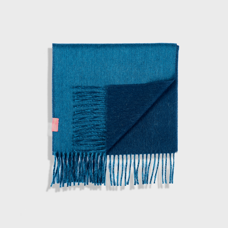 Blue scarf with fringes on a light gray background