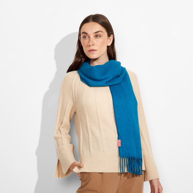 Woman wearing a blue scarf and beige outfit on a white background