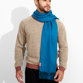 Man wearing a beige sweater and blue scarf against a white background