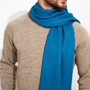 Man wearing a blue scarf and beige sweater on a white background