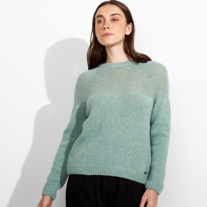 Woman wearing a mint green sweater against a white background