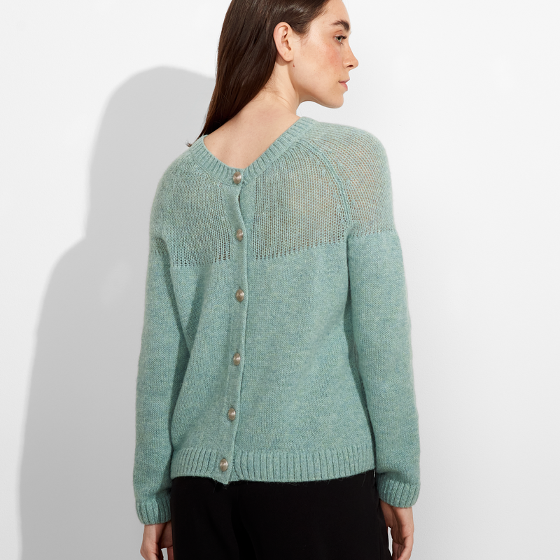 Woman wearing a mint green knitted cardigan against a white background