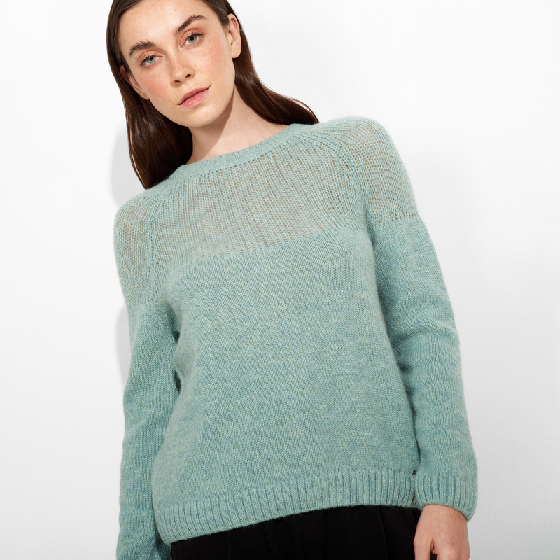 Woman wearing a mint green sweater against a white background