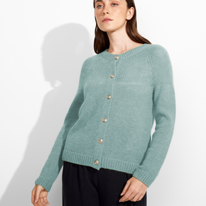 Woman wearing a green cardigan with gold buttons on a white background