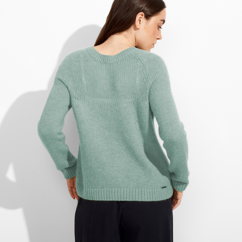 Woman wearing a green sweater against a white background