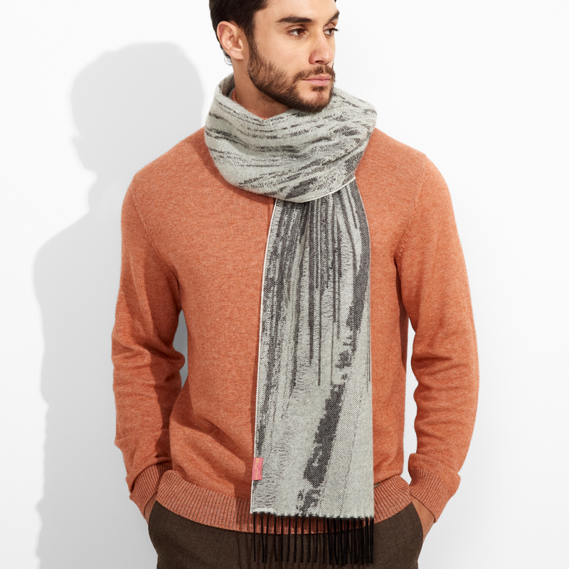 Man wearing a rust-colored sweater and gray scarf against a white background
