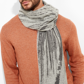 Person wearing a rust-colored sweater and a gray patterned scarf on a white background