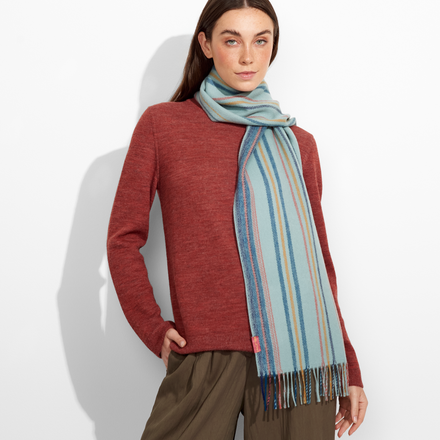Woman wearing a red sweater and striped scarf against a white background