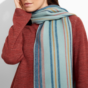 Woman wearing a red sweater and a colorful striped scarf against a plain background