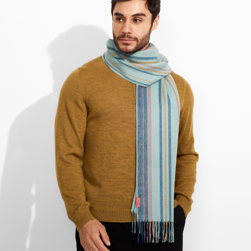 Man wearing a mustard sweater and a colorful scarf against a white background