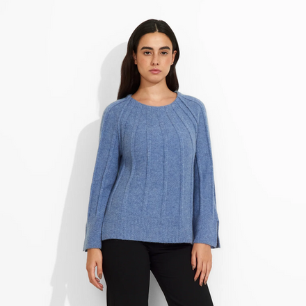 Woman wearing a blue sweater and black pants on a white background