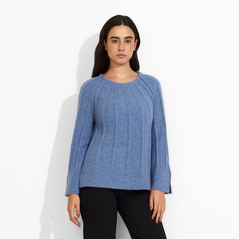 Woman wearing a blue sweater and black pants on a white background