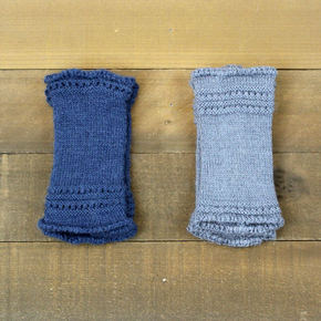 Two blue knitted arm warmers on a wooden surface