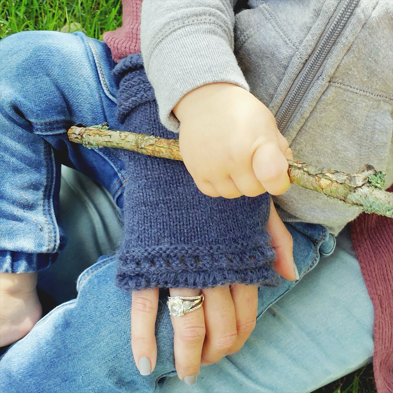 Person wearing a blue fingerless glove holding a stick outdoors