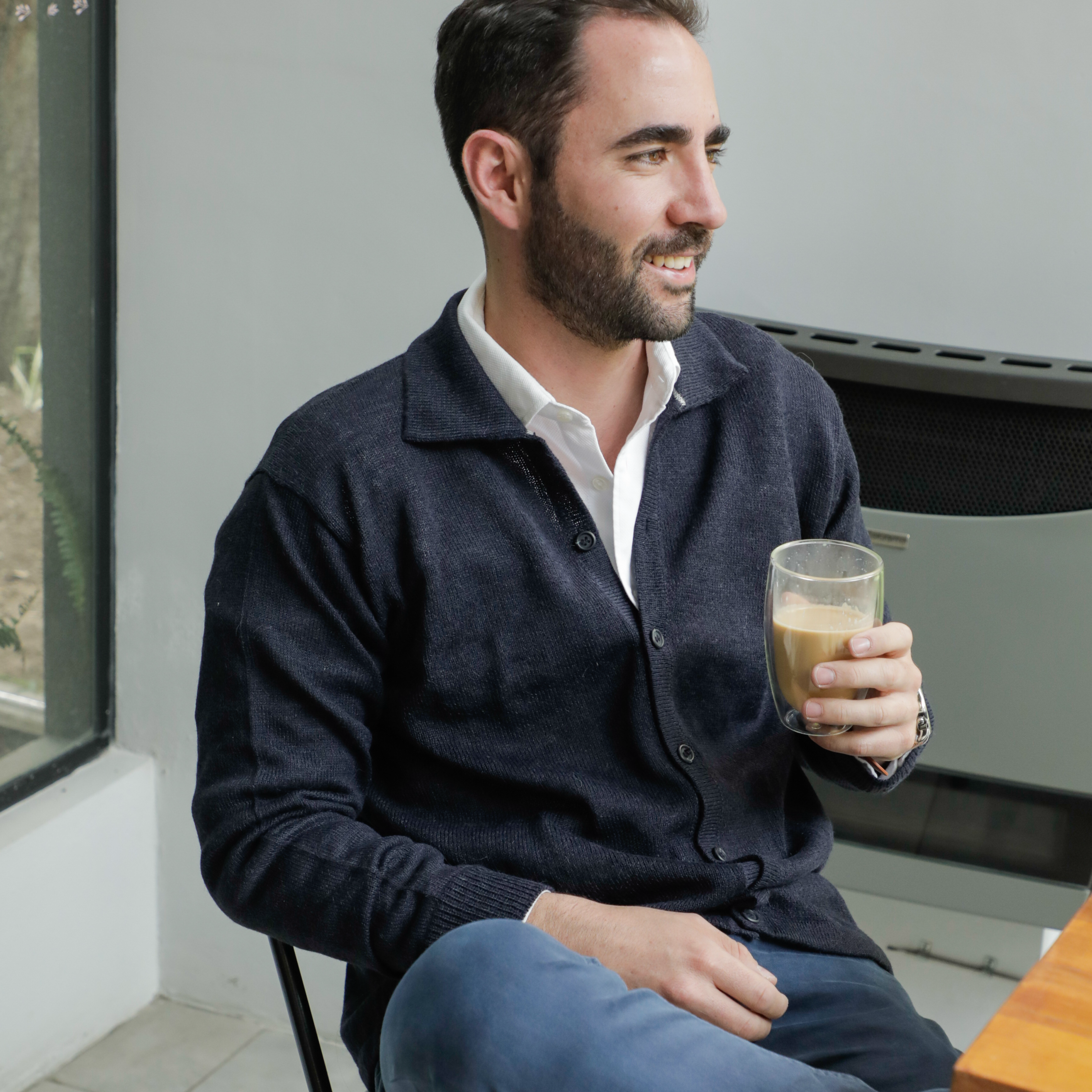 Man sitting on a chair holding a glass of coffee in a kitchen.
