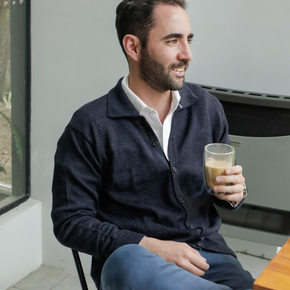 Man sitting on a chair holding a glass of coffee in a kitchen.