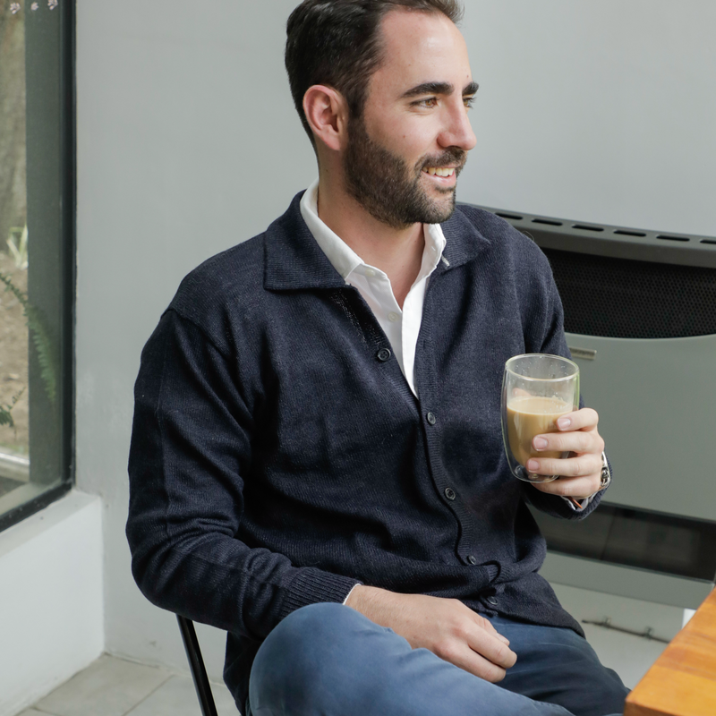 Man sitting on a chair holding a glass of coffee in a kitchen.