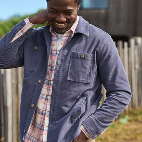 Man wearing a blue jacket over a plaid shirt outdoors