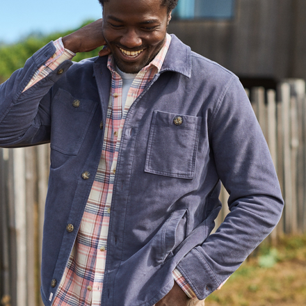 Man wearing a blue jacket over a plaid shirt outdoors