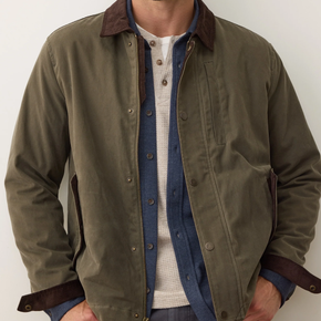 Green jacket with brown collar and trim worn by a person on a white background