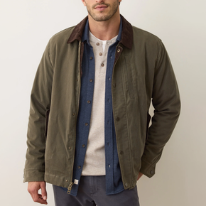 Man wearing a green jacket over a layered outfit on a plain background
