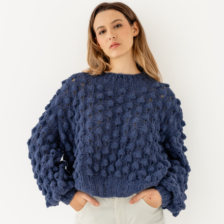 Woman wearing a blue textured sweater against a white background