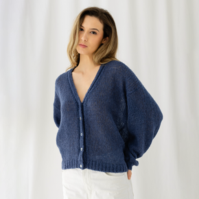 Woman wearing a blue cardigan against a white background