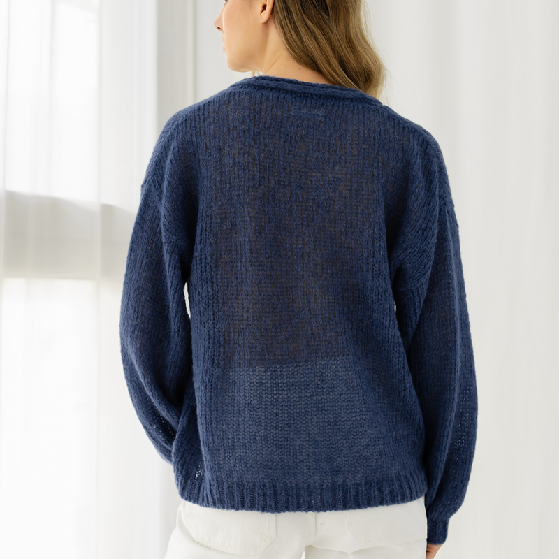 Person wearing a blue knitted sweater against a white background