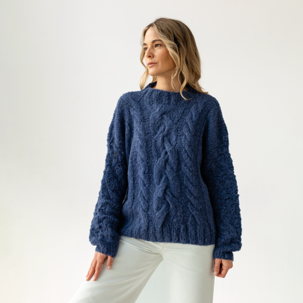 Woman wearing a blue cable knitted sweater against a white background