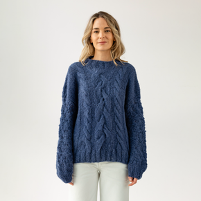 Woman wearing a blue cable knit sweater on a white background