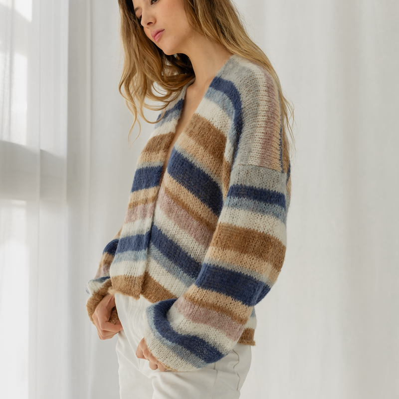 Woman wearing a striped sweater in a bright room with white curtains.