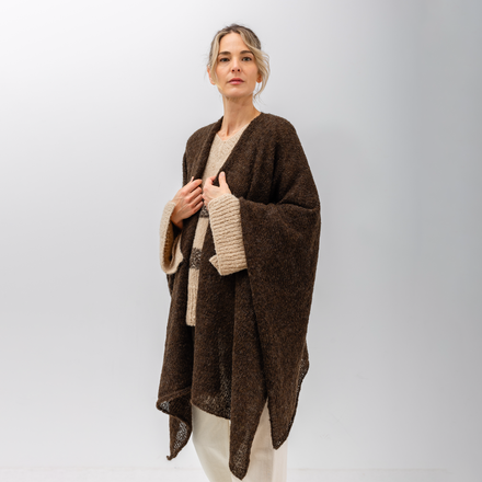 Woman wearing a brown poncho with beige sweater on a white background