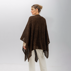 Woman wearing a brown poncho against a white background
