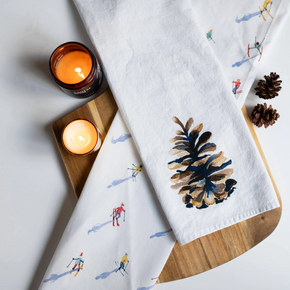 Two white towels with decorative patterns on a wooden board with lit candles.