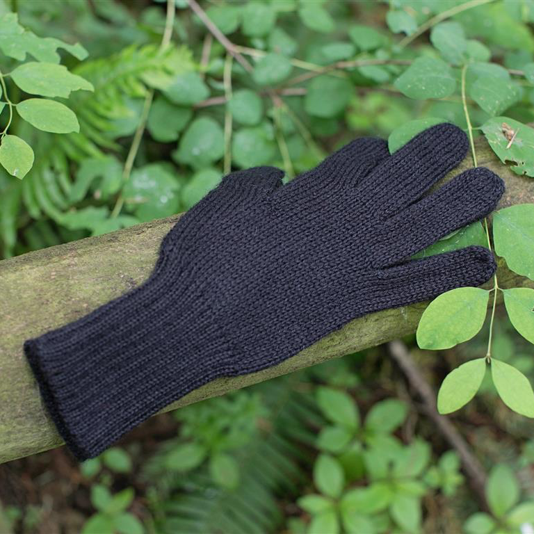 Black glove on a wooden post with green foliage in the background