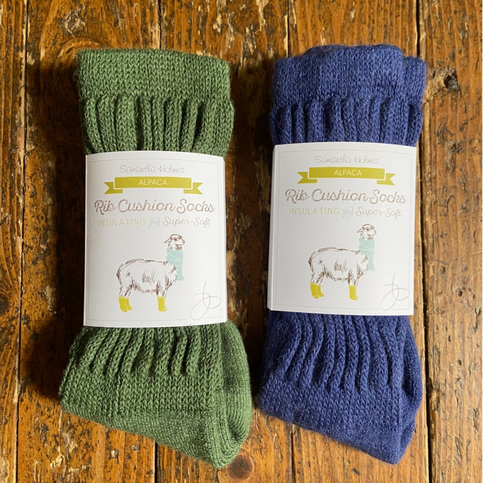 Two pairs of green and blue socks with labels on a wooden surface