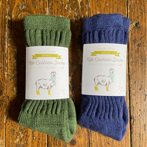 Two pairs of green and blue socks with labels on a wooden surface