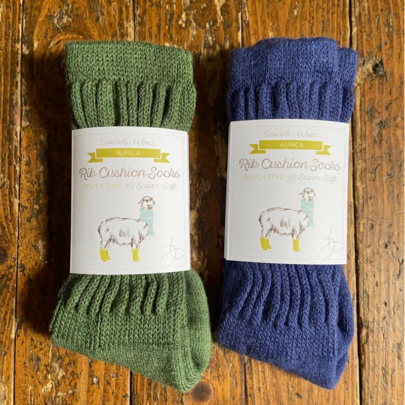 Two pairs of green and blue socks with labels on a wooden surface