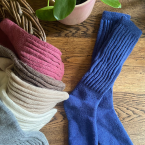 Blue socks on a wooden surface with other pairs of socks in the background.