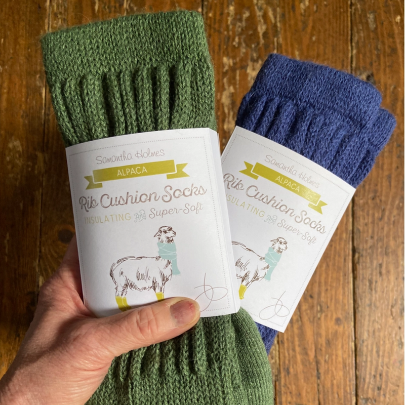 Green and blue cushion socks with packaging held by a hand on a wooden surface