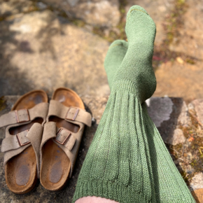 Green socks and brown sandals on a rocky surface