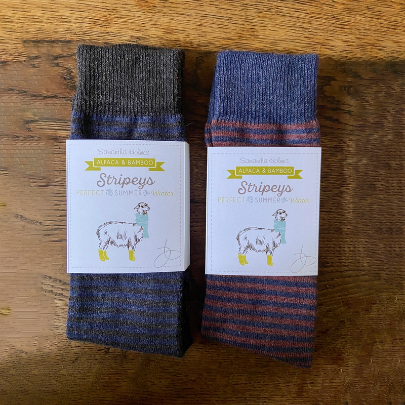 Two pairs of striped socks with matching labels on a wooden surface