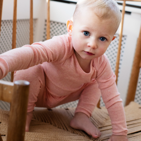 Baby in pink outfit crawling on a wooden floor