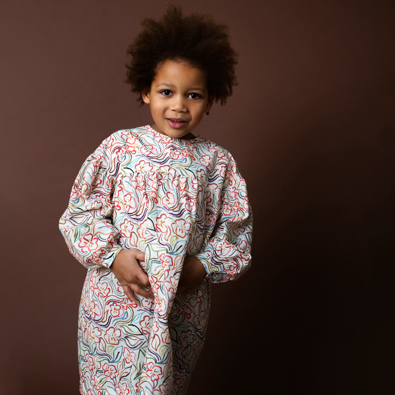 Child wearing a floral patterned dress against a brown background